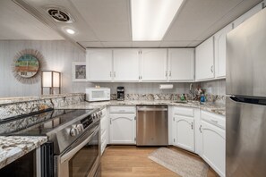 A modern kitchen with white cabinets, a stainless steel refrigerator, a microwave, a dishwasher, and a stove.