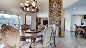 A spacious dining area with a large round table, upholstered chairs, and a modern chandelier. - Fountain Hills Gem With Pool and Great Views! (Fountain Hills)