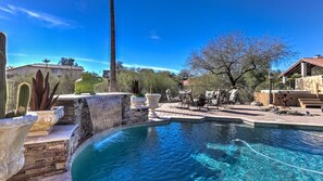A swimming pool with a stone waterfall feature, surrounded by patio furniture and cacti. - Fountain Hills Gem With Pool and Great Views! (Fountain Hills)