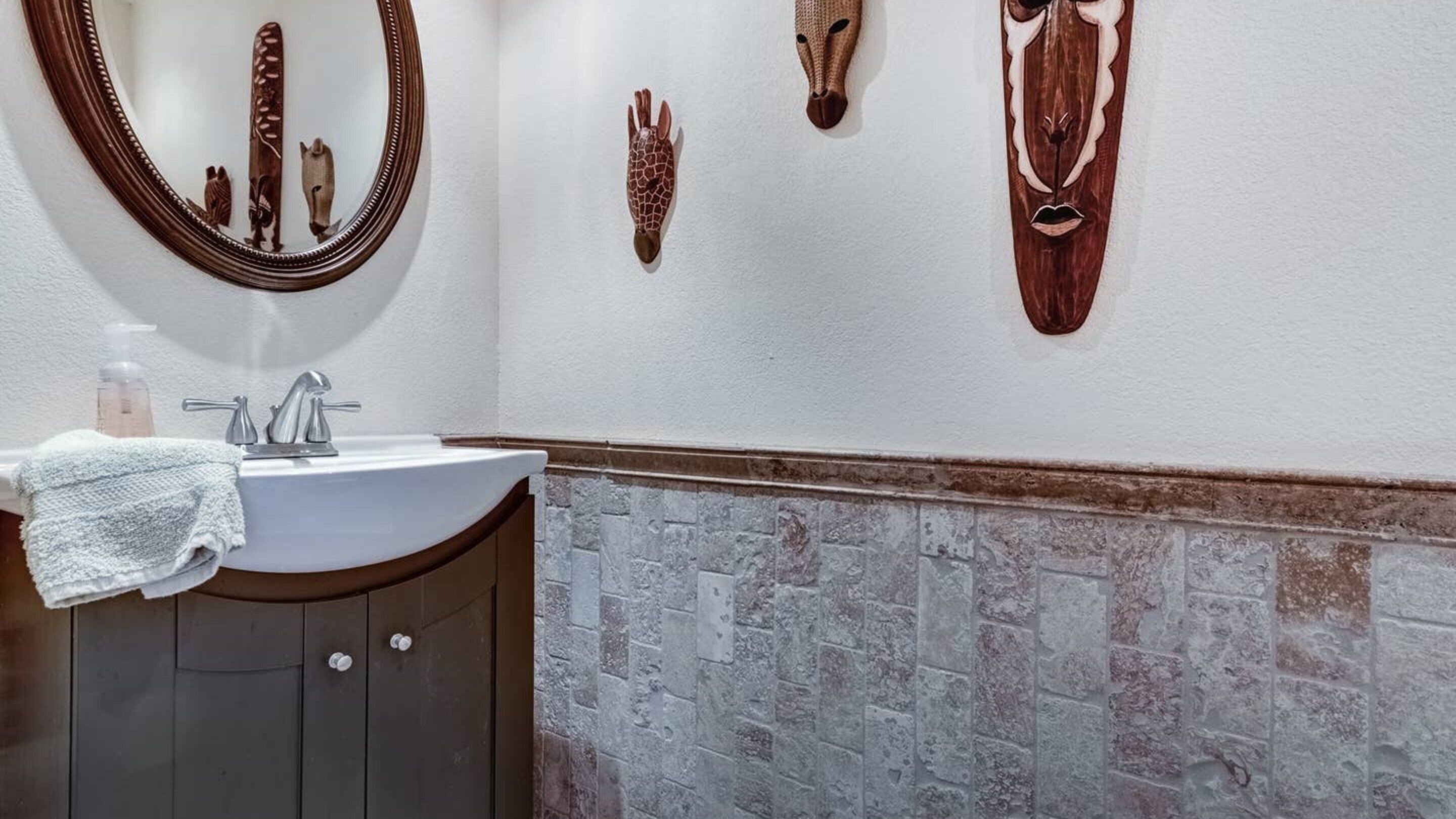 A bathroom with a white sink, a mirror, and decorative wall art including animal heads.