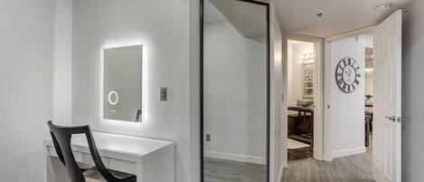 A modern bathroom with a vanity, mirror, and a chair.