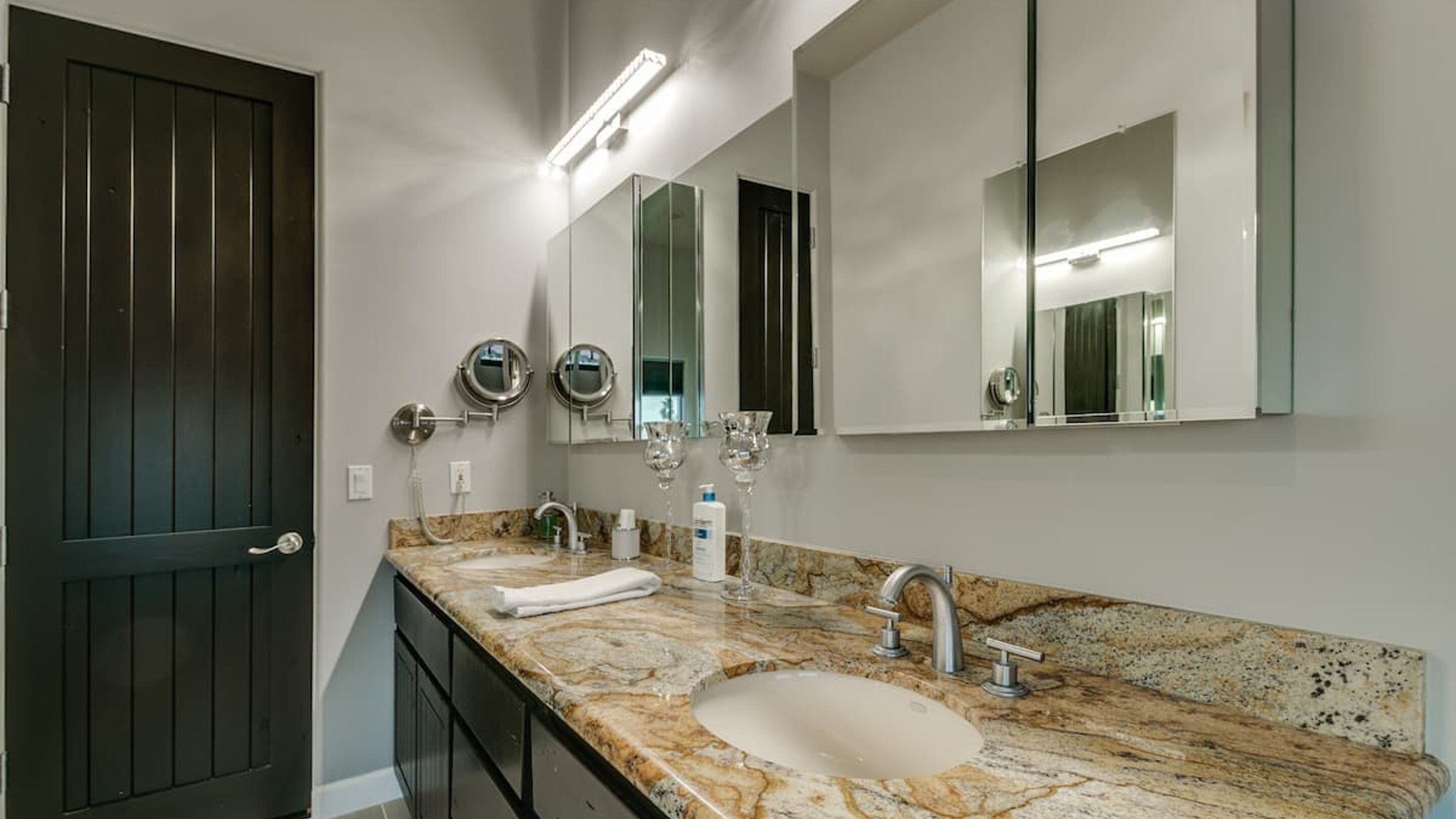 Une salle de bain moderne dotée d’un double lavabo, d’un plan de toilette en marbre et de deux miroirs fixés au mur.