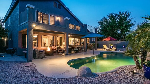 A two-story house with a covered patio area, a swimming pool, and outdoor furniture. - Spectacular Golf Course Home With Pool and Views! (Gilbert)