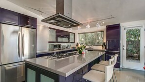 A modern kitchen with a central island, stainless steel appliances, and a large window providing natural light. - Mid-century Modern W/backyard Oasis, Putting Green (Phoenix)
