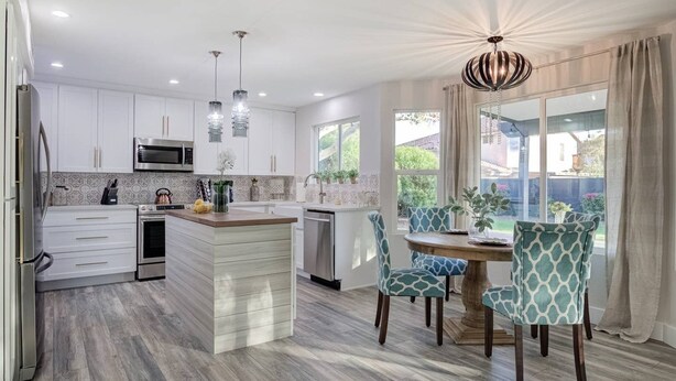 A modern kitchen with white cabinets, a central island, and a dining area with patterned chairs. - Scottsdale Kierland 4 Bdrm W/resort Like Backyard (Scottsdale)