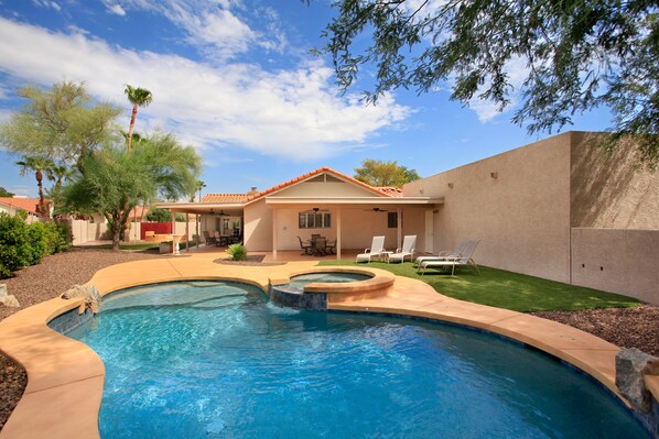 Relax by the curved pool surrounded by lush greenery and a beautifully maintained lawn.