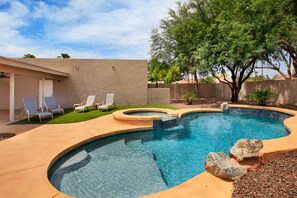 Relax by the pool surrounded by a patio and a large tree, offering a serene atmosphere.