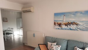 En stue med en lyseblå sofa, et billedramme med et fyrtårn og en radiator.