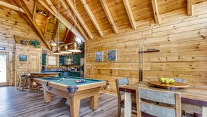A wooden cabin interior with a pool table, dining table, chairs, and a kitchen area. - City View Chalet, City View Chalet, Pool Table, Hot Tub, Free Attraction Tickets (Gatlinburg)