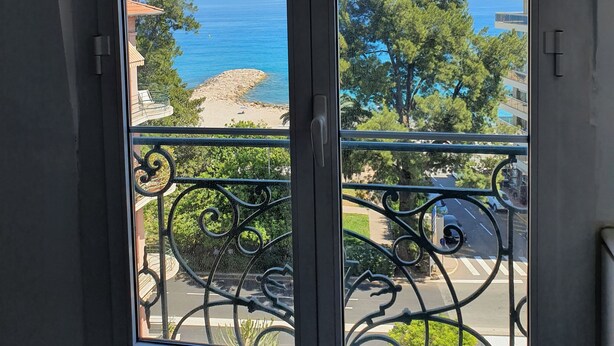 A view from a balcony with a metal railing, overlooking a beach and the sea. - Vista Mare (Menton)