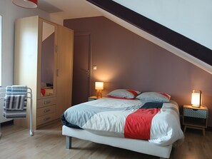 A bedroom with a bed, bedside tables, a wardrobe, and a chair.