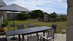 Eine Außenpatio mit Tisch und Stühlen, einem großen Sonnenschirm und einer Steinwand im Hintergrund.