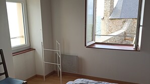 Ein Schlafzimmer mit einem Bett, einem Sessel, einem Fenster und einer Heizung.