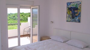 A bedroom with a large bed, a sliding glass door leading to a balcony, a small bedside table, and a colorful rug. - A2 - Modern apt With Balcony, sea View & Parking (Sucuraj)