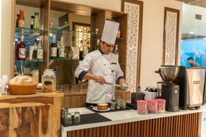 A chef preparing food at a counter with a coffee machine and various condiments.