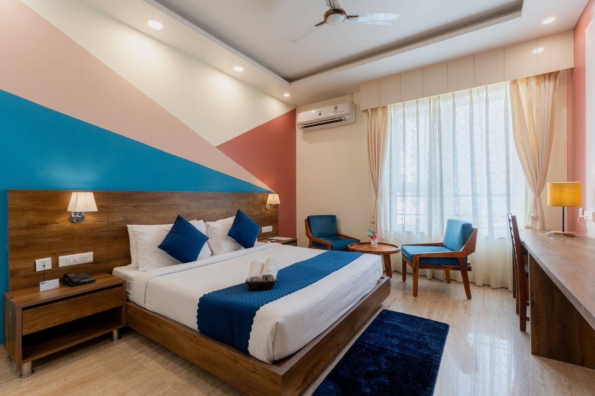 A hotel room with a large bed, bedside tables, a desk, and a chair.