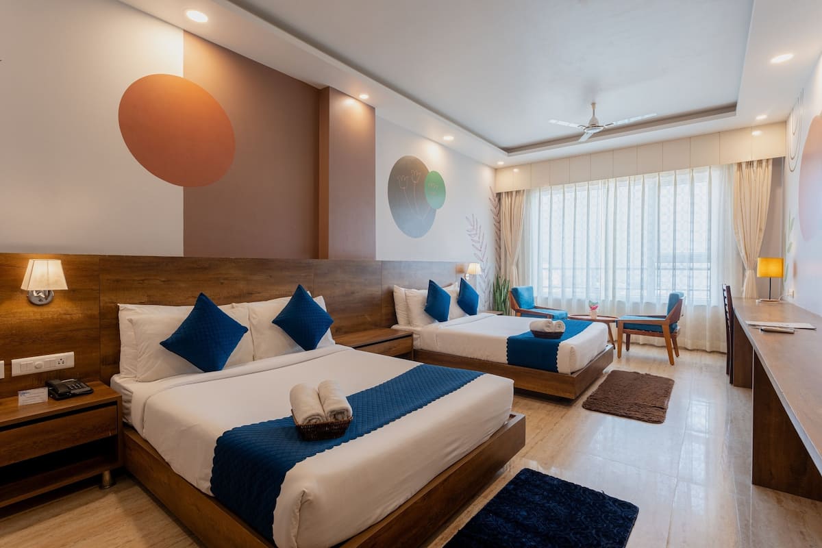 A hotel room with two beds, a desk, and a seating area.