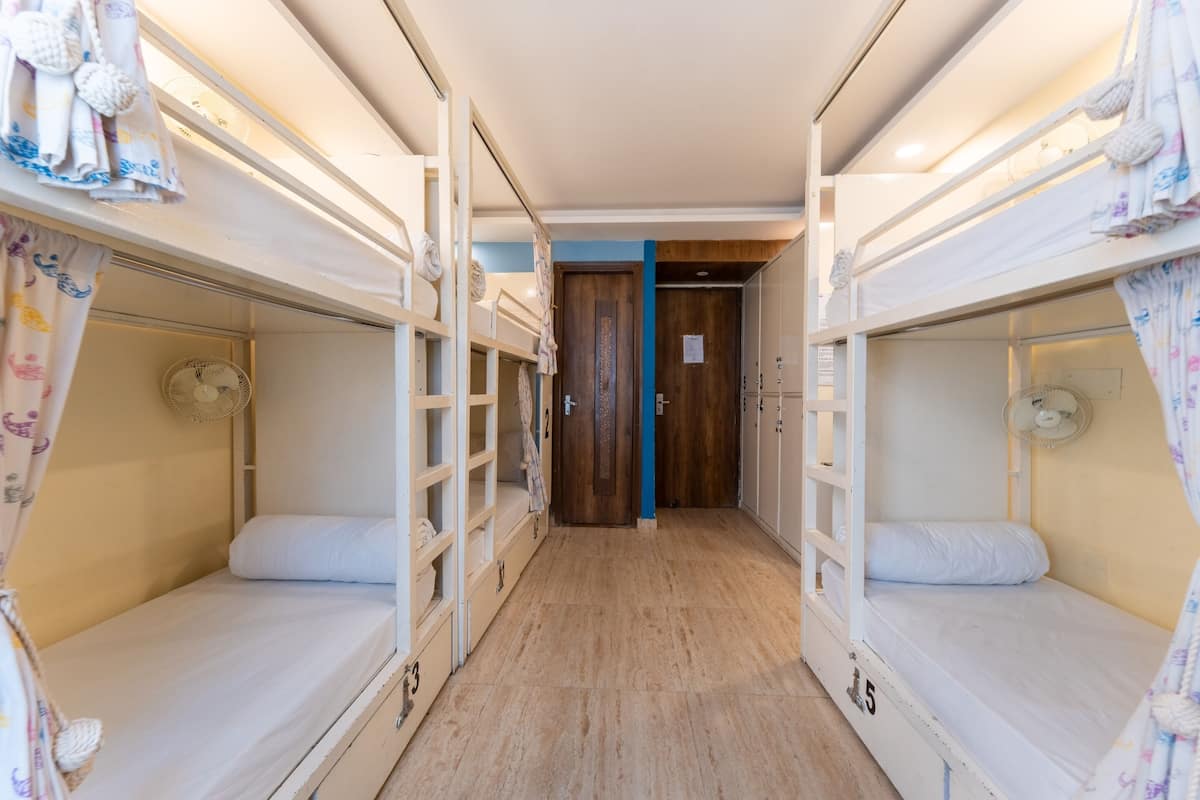 A bunk room with two beds, a wooden floor, and a door leading to another room.