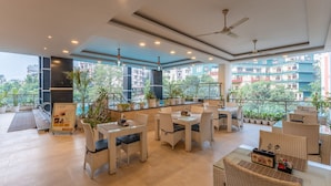 A spacious outdoor dining area with wicker furniture and potted plants, overlooking a cityscape. - Moustache Rishikesh Luxuria - Hostel (Srinagar)