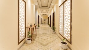 A hotel hallway with a marble floor, potted plants, and decorative screens. - Moustache Rishikesh Luxuria - Hostel (Srinagar)