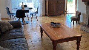 Ein Wohnzimmer mit Couch aus Leder, einem Holztisch und einem Essbereich mit Tisch und Stühlen.