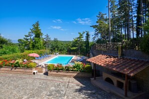 Une piscine entourée de chaises longues, de verdure et d’une pergola.
