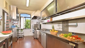 A modern kitchen with stainless steel appliances, a large window, and a view of greenery outside.