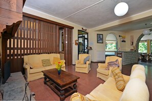 A living room with a sofa, armchairs, a coffee table, and a wooden partition.