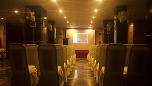A conference room with rows of chairs, a projector screen at the front, and ceiling fans. - Marjan Hotel (Rawalakot)