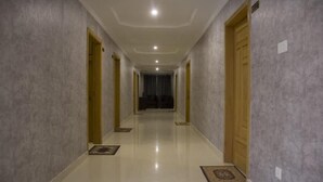 A hallway with a polished floor, wooden doors, and a ceiling with recessed lighting. - Marjan Hotel (Rawalakot)