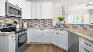 Een moderne keuken met witte kasten, een roestvrijstalen magnetron en een granieten aanrecht.