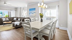 Een moderne woonkamer met een eethoek, met een grote modulaire bank, een houten salontafel en een eettafel met stoelen.