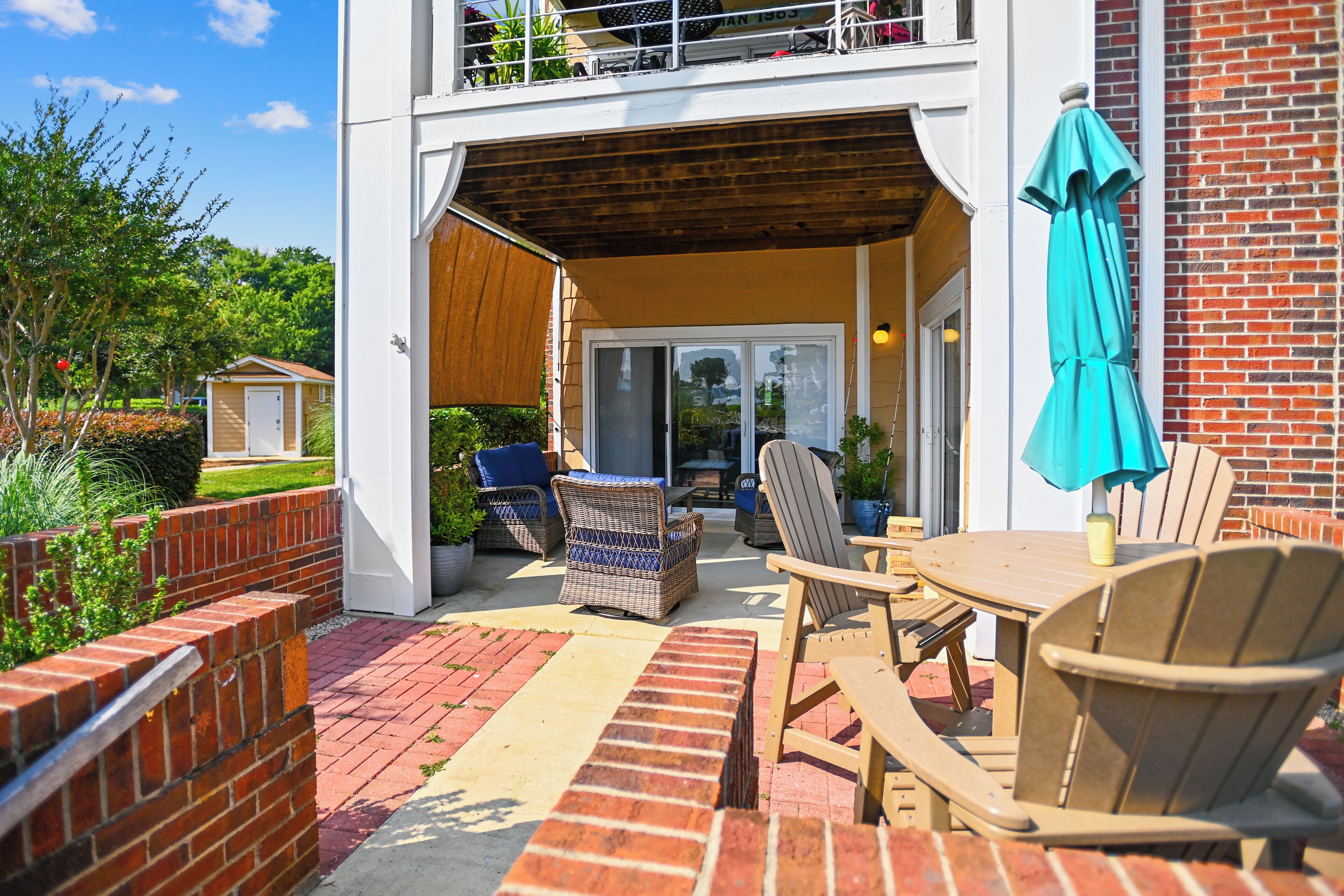 A patio area with outdoor furniture, a brick wall, and a view of the backyard.