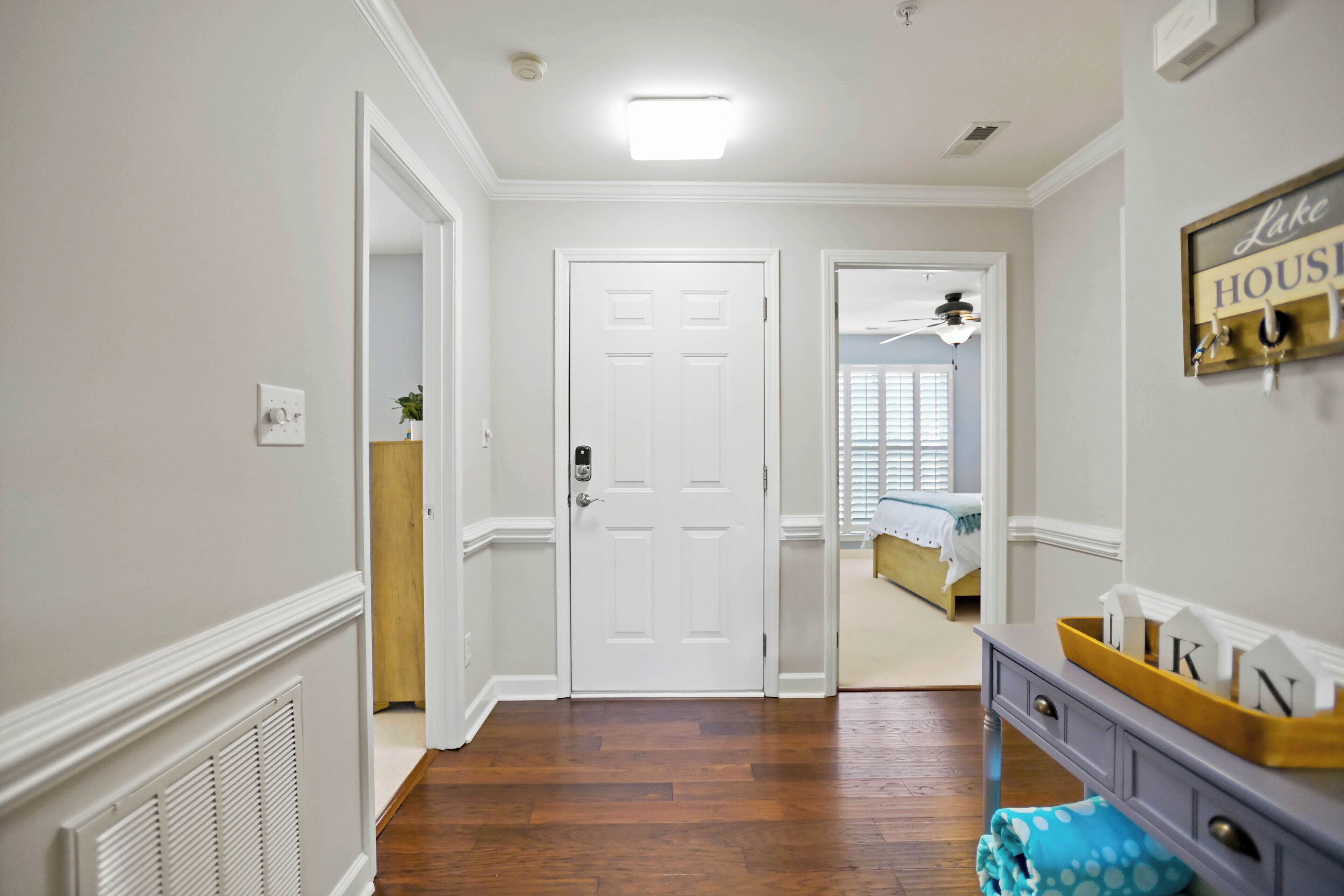 A hallway with a white door, wooden flooring, and a ceiling fan.