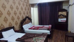 Camera d'albergo con due letti singoli, pavimento in legno, uno specchio e un tavolino con saliera e pepiera.