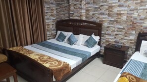 A neatly arranged hotel room with a wooden bed, a nightstand, a telephone, and a patterned wall. - Hotel Al-Markaz (Islamabad)