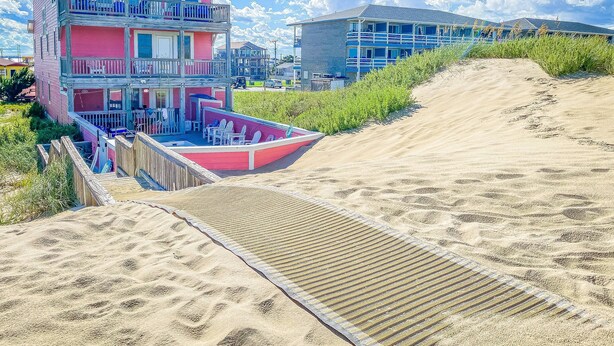 A pink beachfront house with a balcony and a sandy beach in the foreground. - Carolina Sunshine - Nags Head MP 16, Oceanfront, Pool, Hot Tub, Pets OK, Flex Stays (Nags Head)