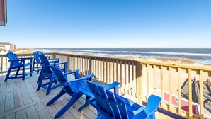 A wooden deck with blue Adirondack chairs facing a beach. - Carolina Sunshine - Nags Head MP 16, Oceanfront, Pool, Hot Tub, Pets OK, Flex Stays (Nags Head)