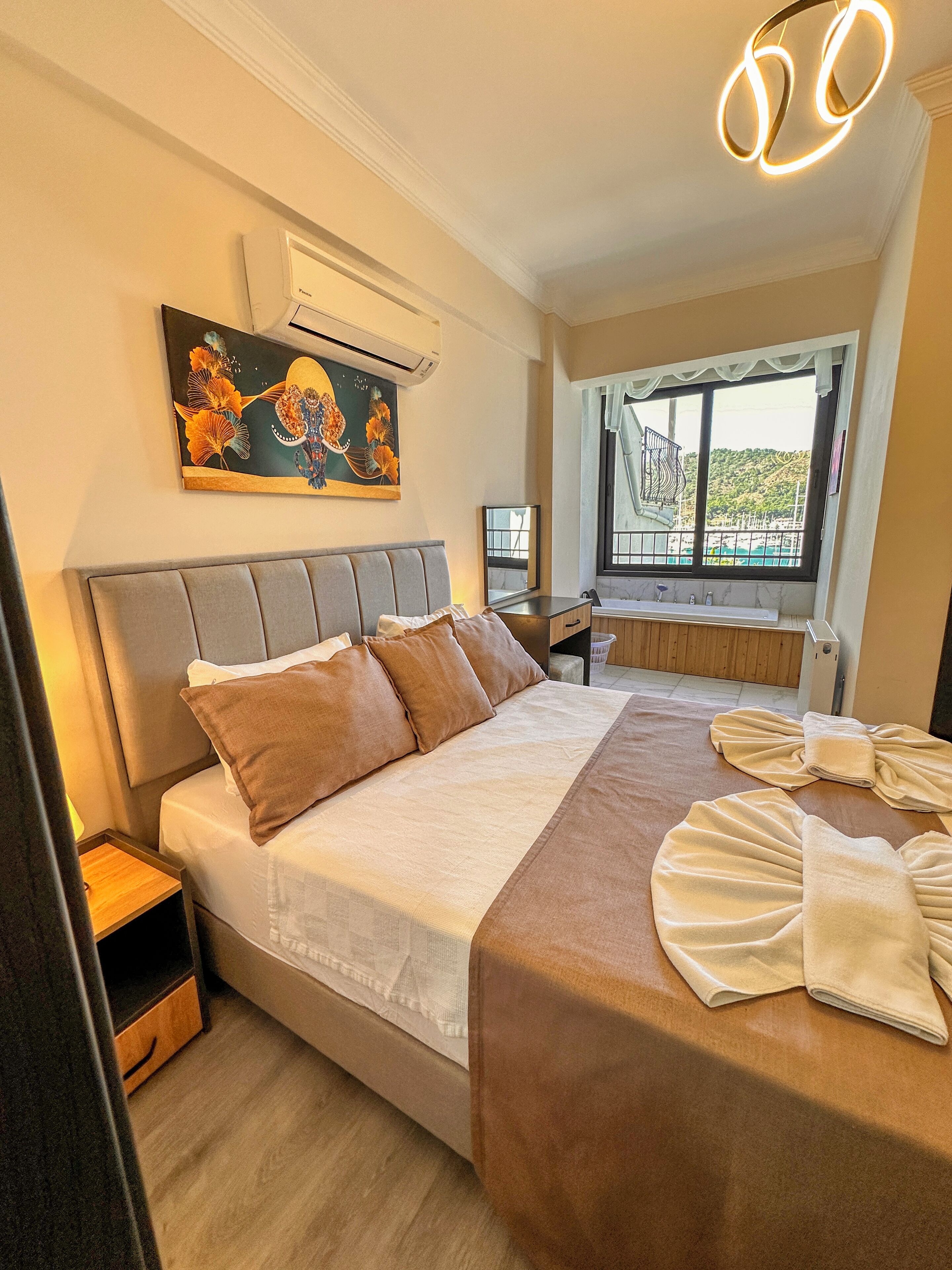 Habitación de hotel ordenada con cama, mesita de noche y ventana con vistas.