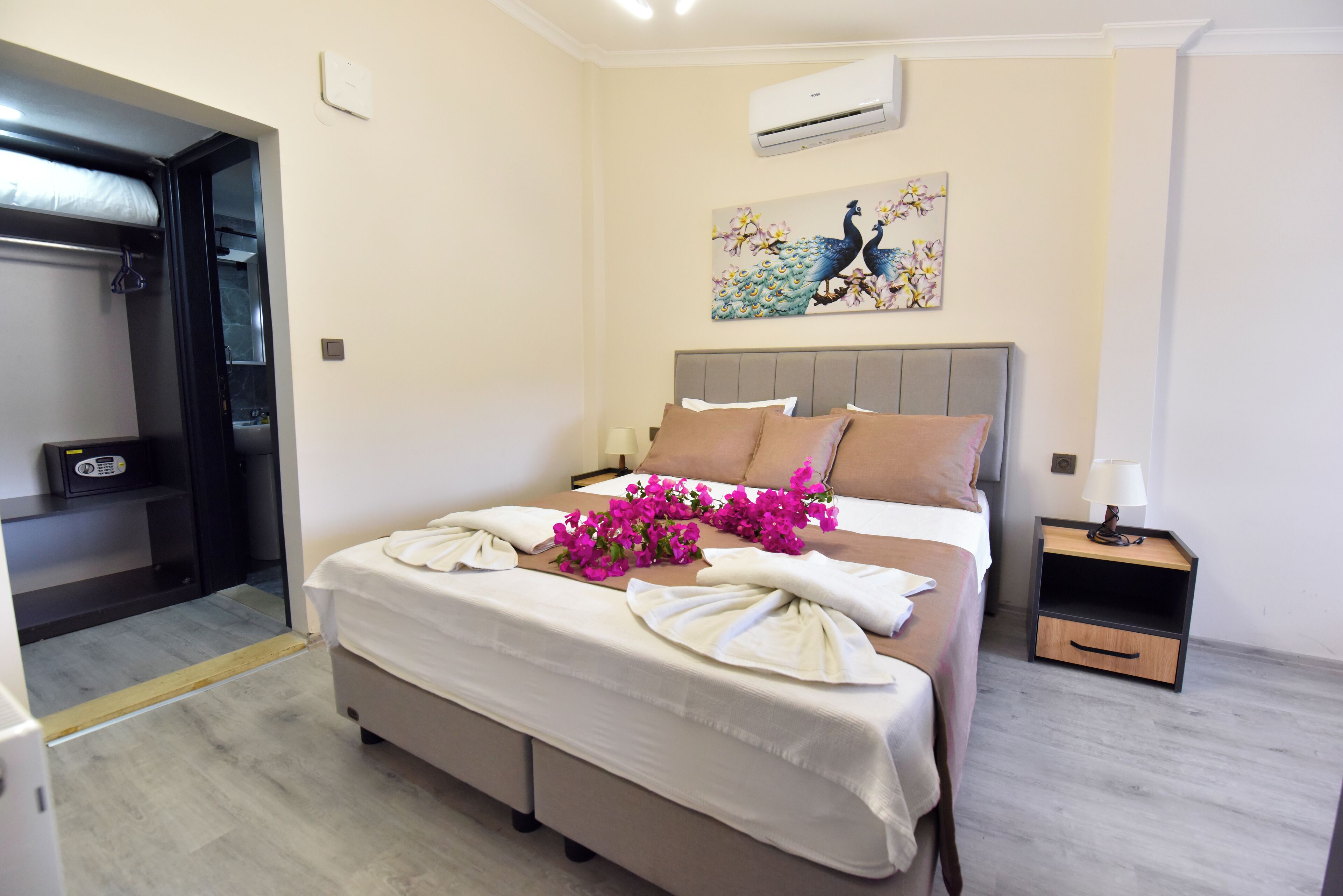 A neatly made bed with a headboard, a bedside table with a lamp, and a wall-mounted air conditioner.