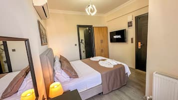 Habitación de hotel con dos camas, televisión, espejo y armario de madera.