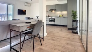 Ett modernt kök med en inbyggd ugn, en matplats med en bänkskiva i marmor och ett stort fönster med utsikt över ett vackert landskap.