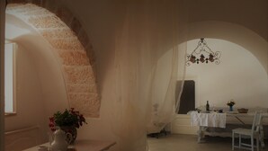 A cozy room with a stone wall, a dining table set with a vase of flowers, and a chandelier.