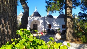 A courtyard with a white building featuring a stone roof and multiple conical structures.