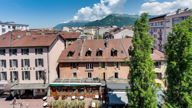 Un edificio con un letrero 'EL DES ALPES' y un restaurante 'Le Saint Germain' en primer plano.