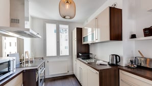 Una cocina moderna con microondas, estufa y lavaplatos. Hay una ventana que proporciona luz natural y vistas al exterior.