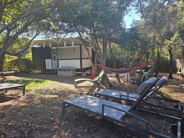 Ein Campingplatz mit überdachter Konstruktion, einer Hängematte und Sitzgelegenheiten im Freien.