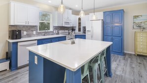 Een moderne keuken met witte kasten, blauwe details en een centraal eiland.