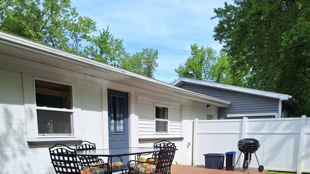 A covered patio with a wooden deck, a barbecue grill, and a table with chairs. -   Beautiful cottage near Lake Michigan. (Coloma)