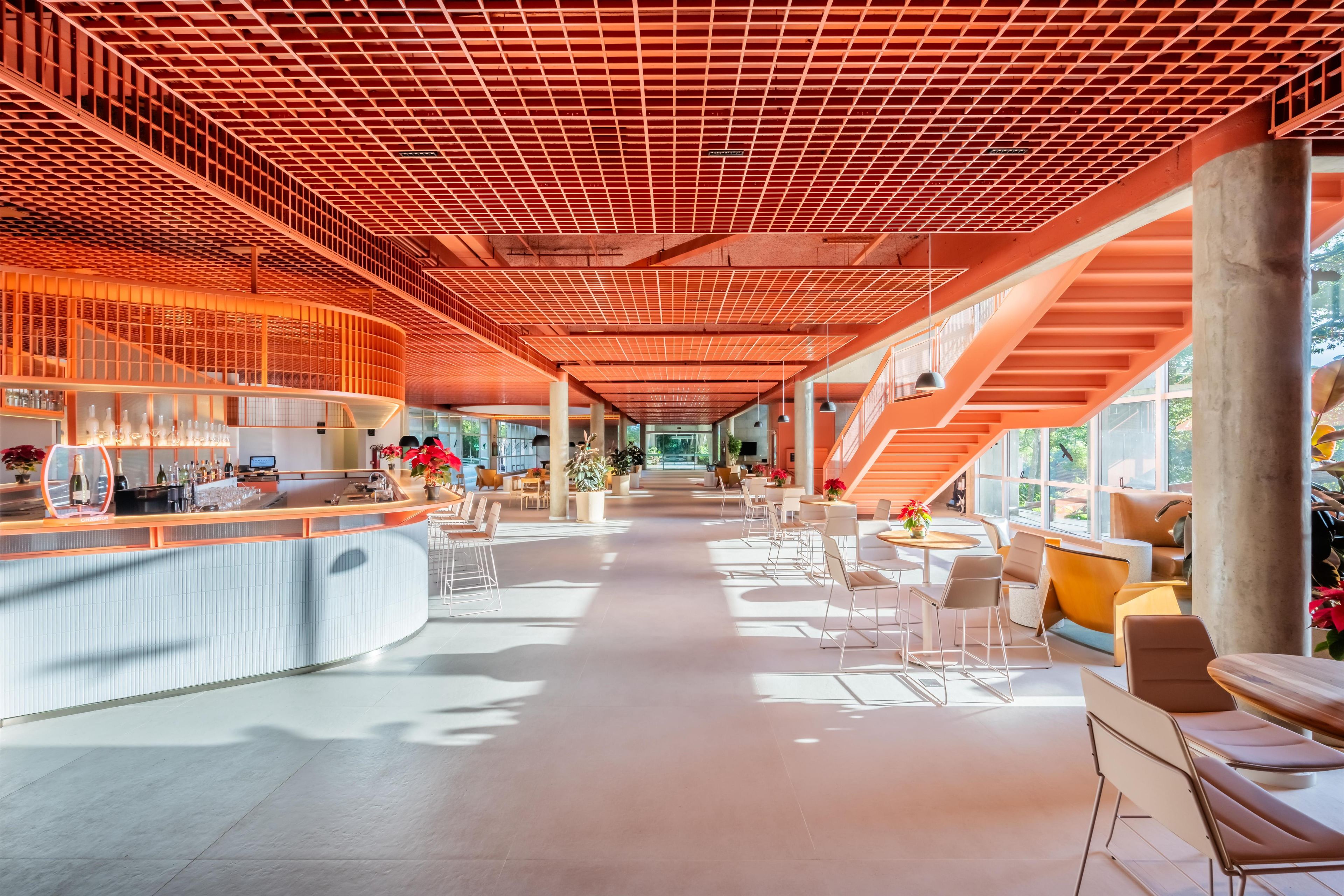 A spacious interior with a modern bar area, seating arrangements, and a staircase leading to upper levels.